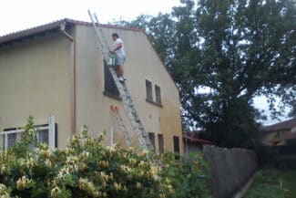 Grande échelle dressée contre une façade beige