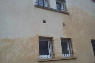 Façade beige nettoyée autour de deux fenêtres