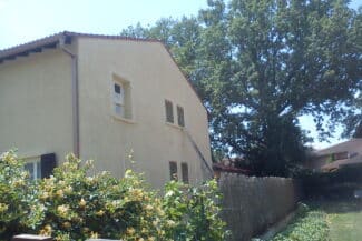 Maison ocre à étage vue depuis le jardin