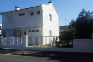 Maison blanche à étage derrière son portail
