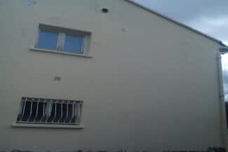 Façade beige avec fenêtre et grille de protection