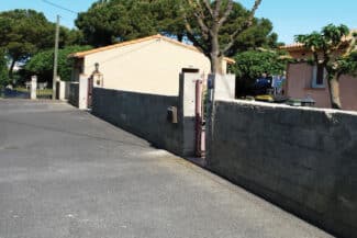 Allée de maison bordée d'un mur de clôture gris