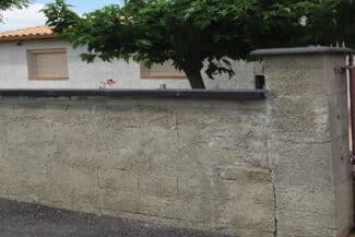 Mur de clôture enduit gris le long d'un jardin