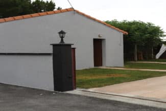 Maison basse blanche avec pilier de portail noir