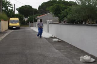 Rue bordée d'un mur de clôture avec camionnette de chantier