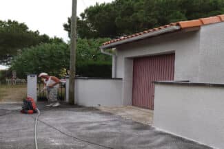 Garage à porte rouge derrière un mur de clôture blanc