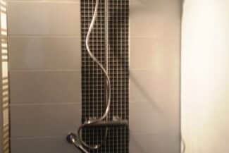 Salle de bains rénovée avec mur clair et radiateur sèche-serviettes