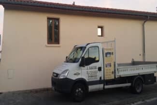 Fourgon de chantier garé devant une façade fraîchement enduite