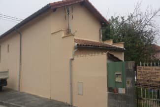 Maison beige à toiture en tuiles avec portail vert