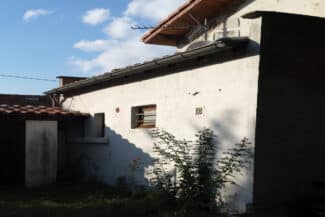 Bâtiment ancien au mur décrépi sous une toiture en tuiles