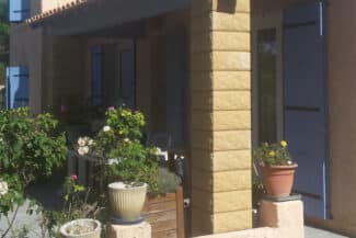 Angle de façade à chaînage jaune bordé de plantes