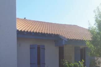 Toiture en tuiles neuves sur une maison aux volets bleus