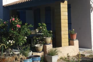 Terrasse fleurie devant une façade à encadrements jaunes