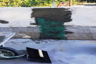 Muret en cours de réparation avec filet de chantier vert