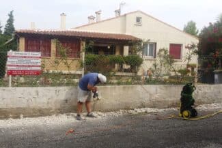 Ouvrier finissant un mur de clôture devant une maison