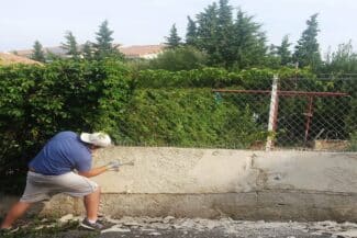 Maçon Appliquant L'enduit Sur Un Mur De Clôture