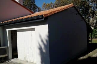 Garage attenant avec porte blanche et mur enduit gris foncé