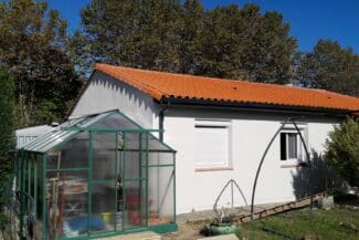 Maison de plain-pied à toiture en tuiles avec serre au jardin