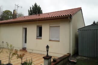 Maison beige à toiture en tuiles avec volets roulants