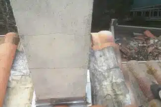 Éléments de zinguerie posés au pied d'un mur de chantier