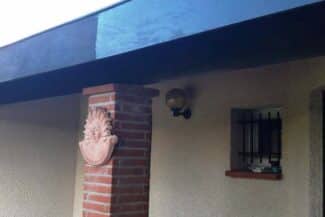 Débord de toiture et planche de rive sombre au-dessus de la terrasse