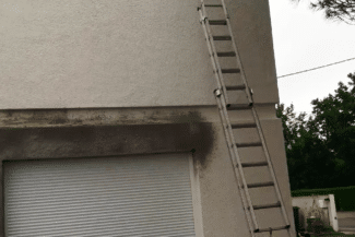 Façade tachée d'humidité avec échelle appuyée avant ravalement