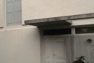 Auvent et porte de garage d'une maison en crépi