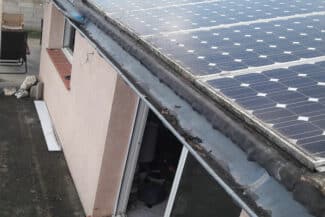 Panneaux solaires installés en bord de toiture le long d'un mur