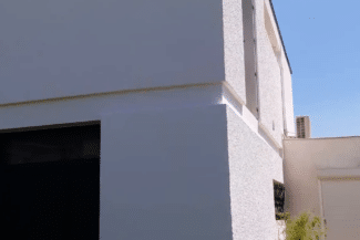 Façade blanche vue d'angle avec porte de garage sombre