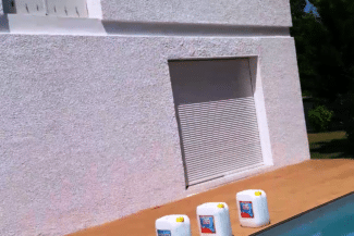 Façade enduite en rose pâle avec volet roulant après rénovation
