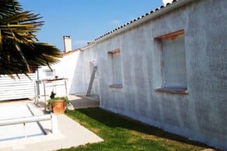 Façade claire en cours de ravalement avec échelle et bâches