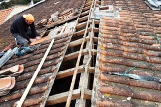 Couvreur posant les liteaux sur une toiture déposée