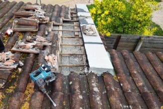 Chantier de couverture avec tuiles déposées et outils sur le toit à Frouzins