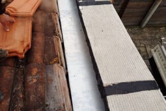 Bande de rive et tuiles en cours de repose sur une toiture à Frouzins