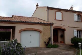 Façade avec porte de garage et encadrements en briques à Tournefeuille