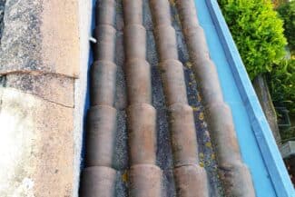 Tuiles anciennes et bâche de protection au pied d'un mur