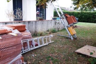 Échelle et monte-tuiles installés dans le jardin pendant le chantier