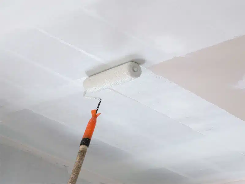 Rouleau de peinture posé contre un mur clair