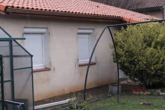 Façade rose pâle à volets roulants à côté d'une véranda