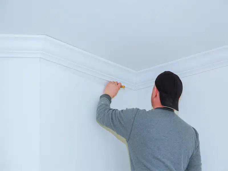 Peintre traçant la finition à l'angle d'un faux-plafond