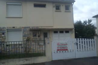 Maison blanche avec garage derrière une clôture