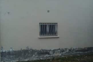 Mur gris avec fenêtre grillagée avant ravalement