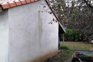 Pignon de maison en enduit clair marqué de fissures