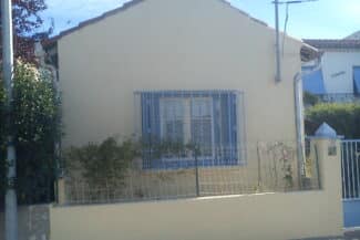 Façade claire et fenêtres à volets bleus après rénovation