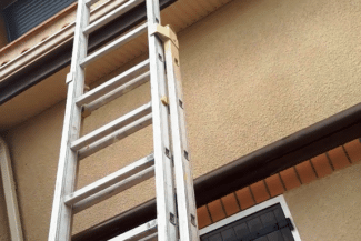 Échelle dressée contre une façade beige