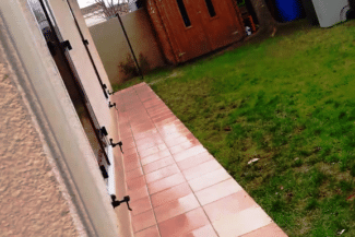 Terrasse carrelée le long d'une façade et d'une pelouse