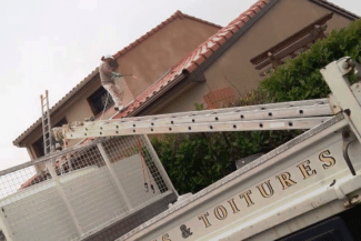Échelle télescopique dressée le long d'une façade pour nettoyer la toiture