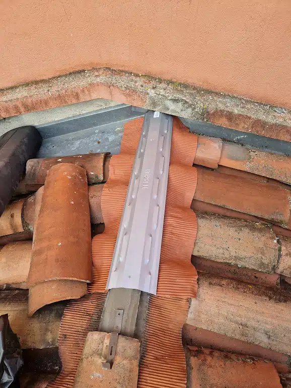 Faîtage en cours de dépose avec tuiles empilées