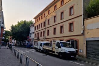 Façade d'immeuble et véhicules de chantier en bas de rue à Toulouse