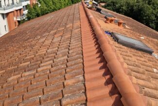 Toiture d'immeuble aux tuiles canal entretenues à Toulouse